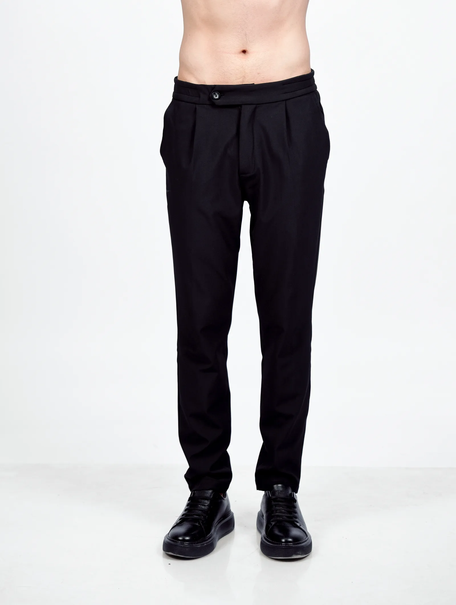 Pantalon homme avec pli marqué et ceinture avancée, porté de face beige foncée
